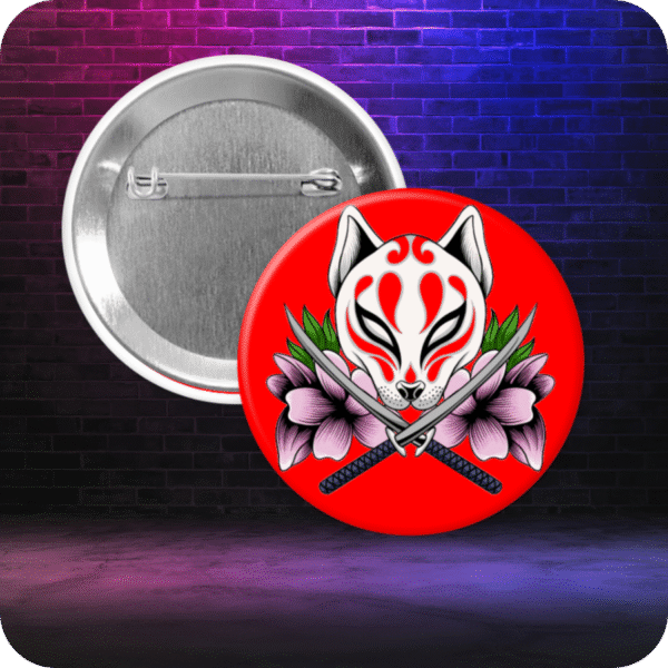 Pinback button featuring a stylized orange and white Japanese kitsune mask. Mask is flanked by pink and purple flowers with two katana swords chris-crossed beneath the mask. Button is displayed with metal backing on a gradient graffiti-style background.