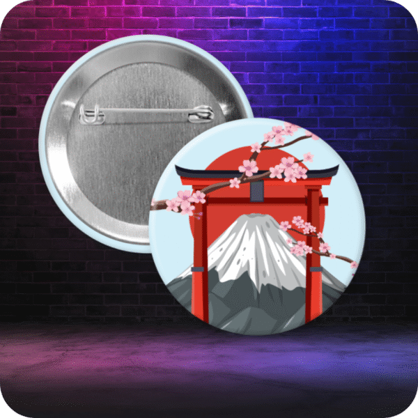 Pinback button featuring an image of Mount Fuji in Japan with a red torri and pink cherry blossoms in the foreground. All set against a blule sky. Button is displayed with metal backing on a gradient graffiti-style background.